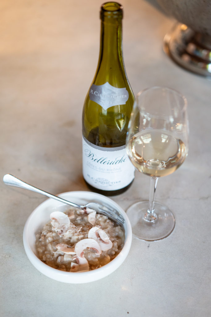 Cote du rhone white wine in a glass next to a bowl of mushroom risotto by michelin starred chef, Chris Godfrey at Shoreditch Treehouse
